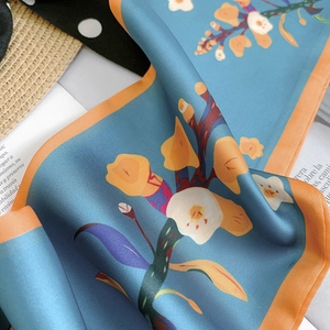 Close-up of floral print silk scarf with smooth satin texture and elegant blue patterns