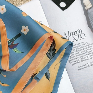 Detail showing the floral pattern and silk-like texture of a navy and yellow scarf