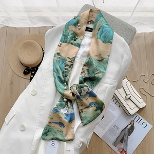 Detail showing elegant mountain print silk scarf with luxury pearl and metal chain accents