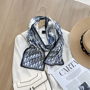 Detail of blue and white landscape print silk scarf styled on a white blazer
