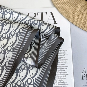 Detailed macro shot of elegant silk-like scarf with abstract fish print and striped edges