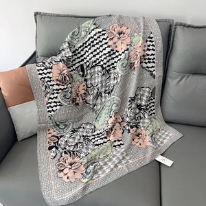 Detail of floral and paisley patterned scarf with houndstooth print on grey sofa