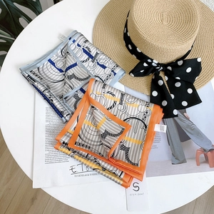 Detailed close-up of chain print silk scarves with branding tags on a white table