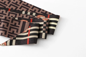 Macro view of floral silk skinny scarf with geometric belt pattern and texture detail