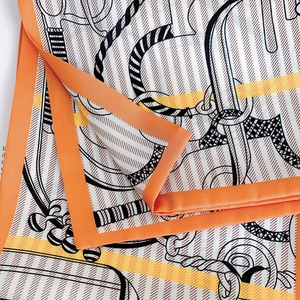 Close-up of silk scarf with equestrian print and vibrant orange border detail