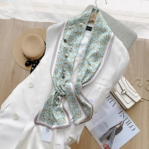 Detail van lichtblauwe satijnen sjaal met parels en kettingpatroon op een blazer