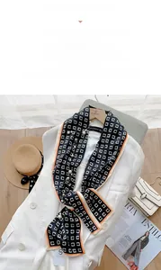 Détail d'un foulard en satin bleu marine avec cadres blancs, bords orange et perles