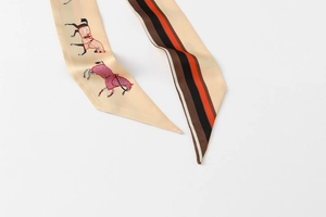 Detailed view of beige twilly scarf featuring horse motifs and tricolor striped pattern