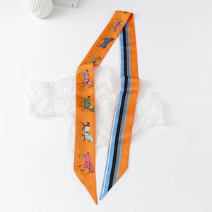 Detail of a double-sided silk twilly scarf featuring horse motifs and stripes in orange
