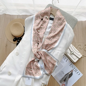 Roze satijnen sjaal met paardenbitprint en pareldetails op een witte blazer display