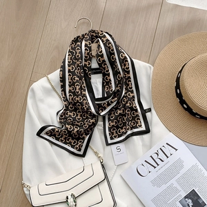 Detail van satijnen sjaal met paardenbit-print op witte blazer voor elegante look