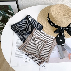 Détail de foulards en satin rayé noir et beige posés sur un magazine élégant