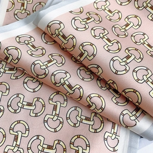 Detail van lichtroze satijnen sjaal met paardenbitprint toont gladde glanzende stof