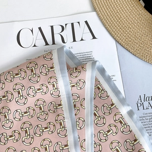 Detail van roze satijnen twilly sjaal met bit-print en gestreepte rand op accessoires