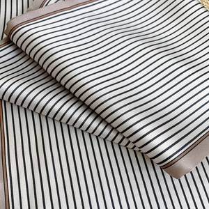 Vue détaillée d'une écharpe en satin rayée noir et blanc avec bordure marron élégante