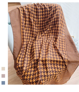 Detail view of large houndstooth scarf draped on a chair with texture in brown and yellow