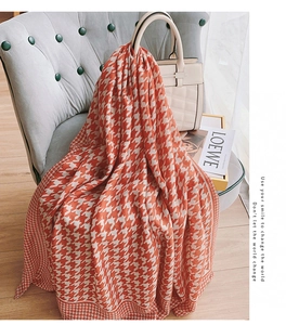 Classic orange houndstooth scarf draped on a velvet chair with stylish props
