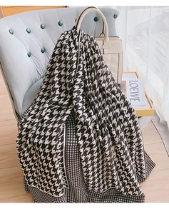 Detail of classic houndstooth scarf with fine black border draped on a white handbag