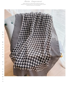 Detail of premium houndstooth scarf draped on a chair with soft interior lighting