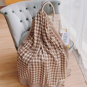 Classic brown houndstooth cotton linen scarf draped over a grey chair in cozy room