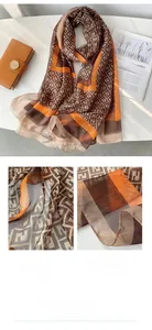 Detailed view of brown and orange silk scarf featuring classic monogram pattern edge stitching