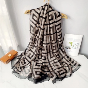 Lightweight black and white polka dot beach shawl hanging on a wooden hanger on table