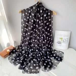 Detail of sheer black scarf with white polka dots draped on a wooden hanger