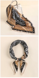 Detail of paisley pattern silk scarf draped on a white handbag with elegant golden borders