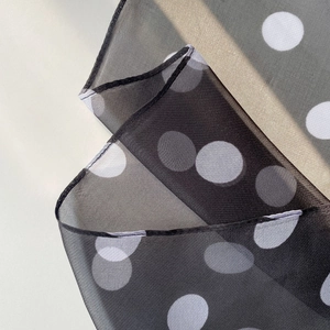 Macro detail of lightweight sheer polka dot scarf showing soft fabric texture and fine hem