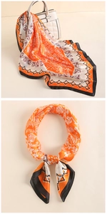 Close-up of vintage orange silk square scarf with paisley patterns and golden edges