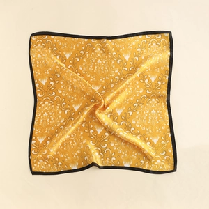 Detail of yellow silk scarf featuring white baroque scroll patterns and black border edges