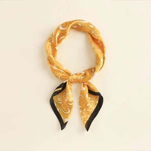 Detail of silk-like yellow paisley square scarf showing intricate pattern and black hem