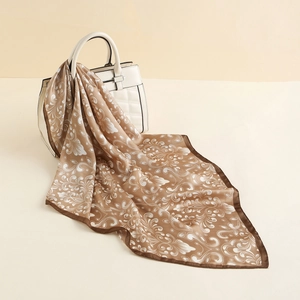 Close-up of retro paisley silk scarf tied to a white handbag on a neutral background