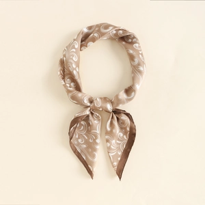 Close-up of champagne silk scarf with white paisley patterns and dark brown edges