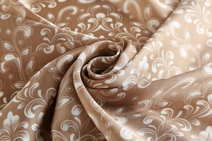 Detailed view of the silk-like scarf featuring elegant paisley patterns in brown and white