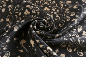 Close-up of vintage floral silk scarf with golden scroll patterns on black fabric