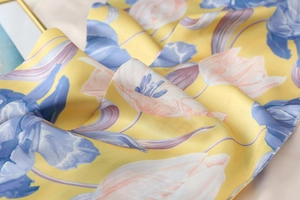 Detail of silk satin floral scarf fabric with tulip print on lemon yellow background