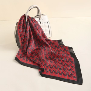 Elegant red faux silk square scarf with paisley pattern draped on a white handbag