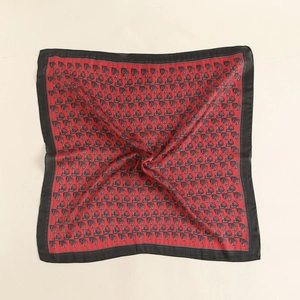 Detail of red silk square scarf featuring classic chain patterns and black borders