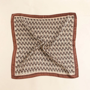 Close-up of silk square scarf featuring vintage equestrian buckle patterns and golden edges