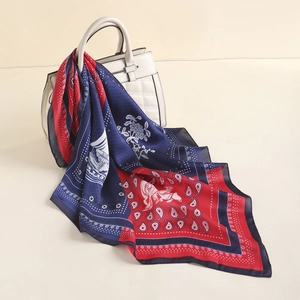 Detail of silk scarf with red and navy paisley patterns draped on a white handbag