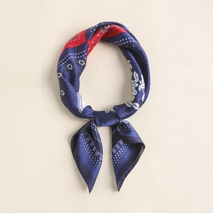 Close-up of vintage silk scarf featuring navy and red paisley pattern with gold edges