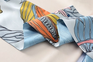 Detailaufnahme des Seidenschals mit blauen und orangen floralen Print-Mustern