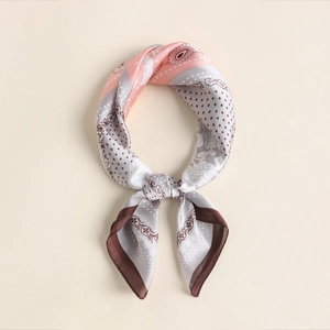 Detail of silk square scarf featuring paisley patterns and elegant gold trim edges