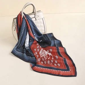 Detail view of paisley silk-feel scarf with camel art draped on white handbag