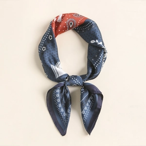 Detail of a silk paisley bandana styled as a bow tie with elegant gold trim edges
