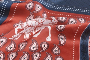 Macro shot of paisley pattern and horse print on silk-like scarf with gold edging