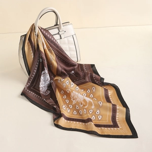Detail of retro paisley silk scarf draped over a quilted bag with golden leaf edges