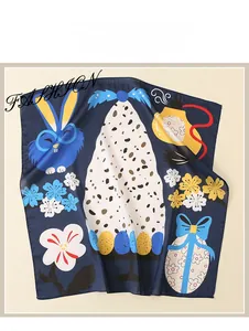 Détail d'un foulard en soie bleu foncé avec illustrations de lapins et motifs floraux