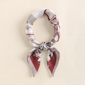 Detail of silk square scarf tied in a bow with paisley floral patterns and gold edges